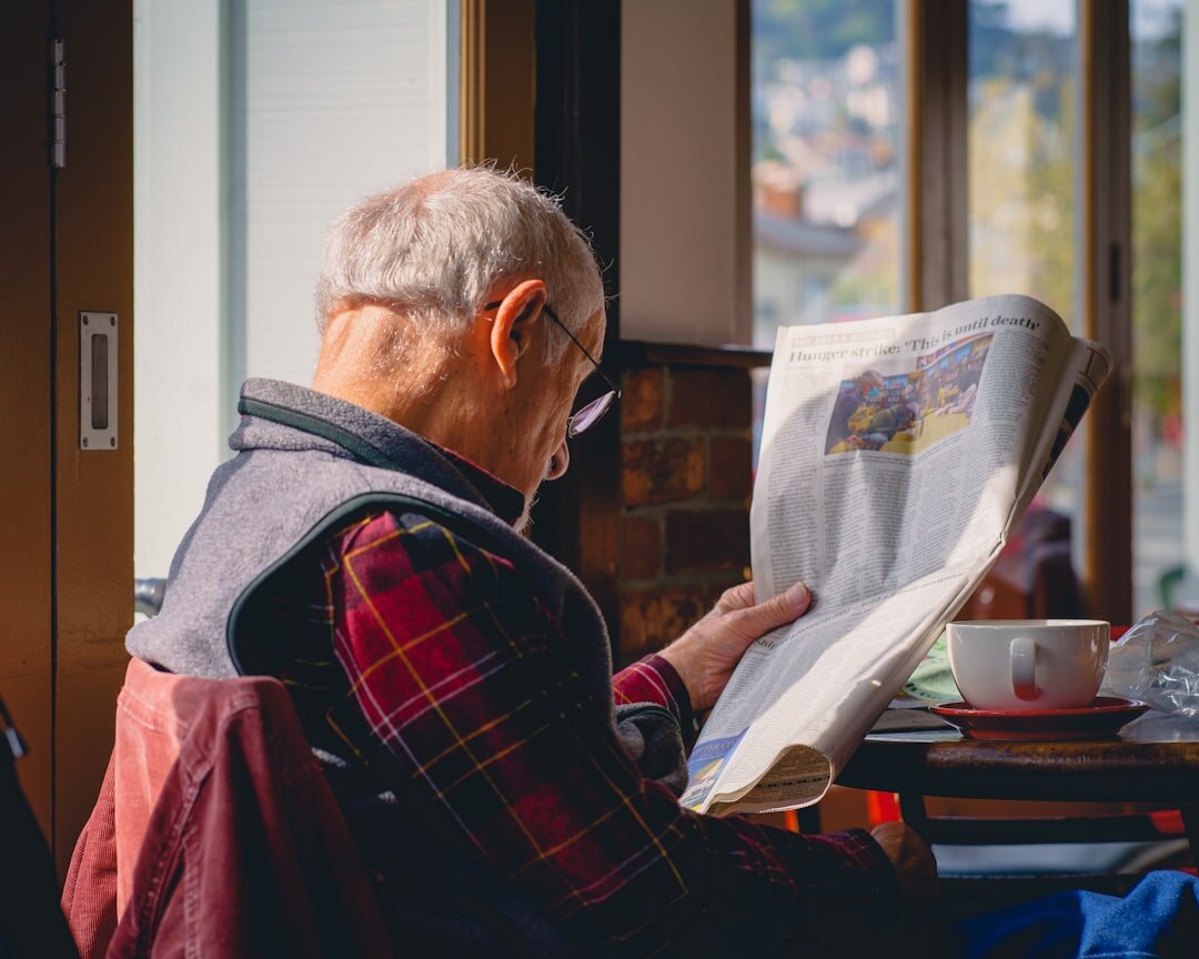 Senior citizens reading newspapers and chatting at a table